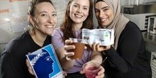 Tre kvindelige studerende fremviser vegansk dessert